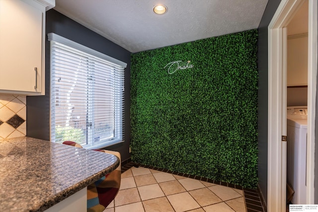 tiled dining room featuring washer / clothes dryer and a textured ceiling