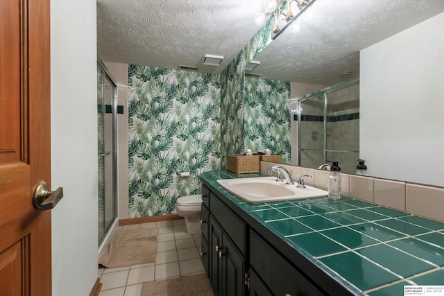 bathroom with tile patterned floors, vanity, walk in shower, and a textured ceiling