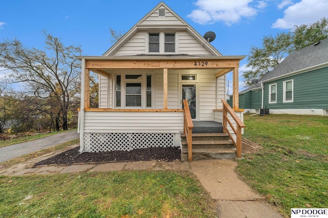 bungalow-style house featuring a porch, a front lawn, and central air condition unit