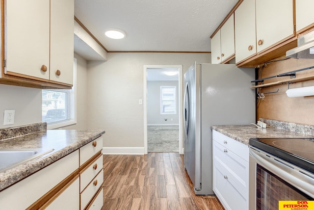 kitchen featuring white cabinets, appliances with stainless steel finishes, light hardwood / wood-style flooring, and plenty of natural light