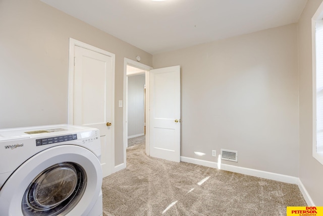 laundry area with washer / clothes dryer and light colored carpet