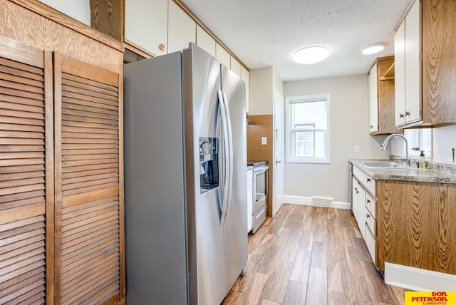 kitchen featuring white cabinets, sink, light hardwood / wood-style flooring, a textured ceiling, and stainless steel appliances