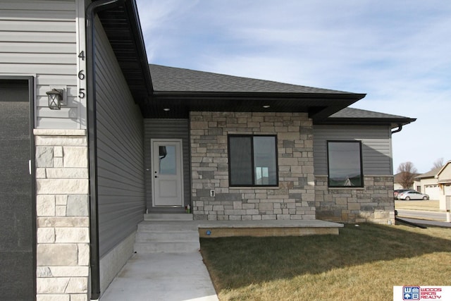 entrance to property featuring a garage and a lawn