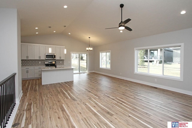 kitchen featuring light hardwood / wood-style flooring, hanging light fixtures, stainless steel appliances, white cabinets, and decorative backsplash