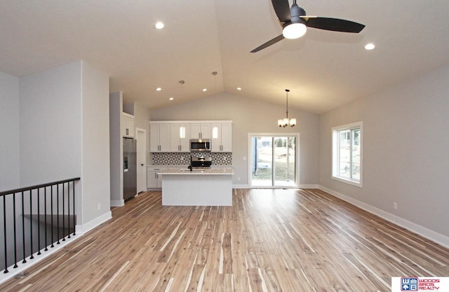 unfurnished living room featuring ceiling fan with notable chandelier, high vaulted ceiling, and light wood-type flooring