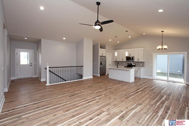 kitchen with lofted ceiling, white cabinetry, a center island, stainless steel appliances, and backsplash