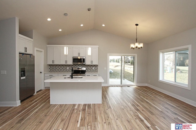 kitchen featuring tasteful backsplash, appliances with stainless steel finishes, hanging light fixtures, and white cabinets