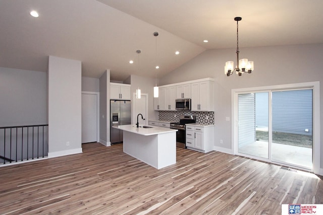 kitchen with stainless steel appliances, tasteful backsplash, hanging light fixtures, and white cabinets