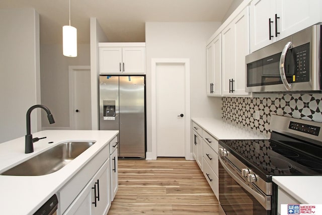 kitchen featuring pendant lighting, sink, appliances with stainless steel finishes, white cabinetry, and backsplash