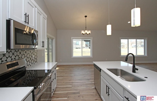 kitchen featuring sink, white cabinetry, decorative light fixtures, appliances with stainless steel finishes, and backsplash