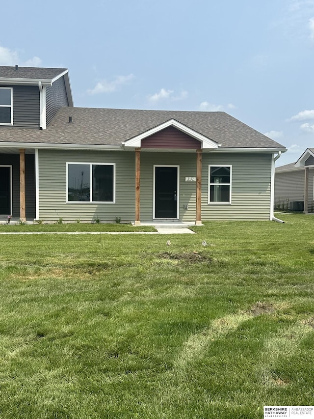 view of front of house with a front yard and a shingled roof