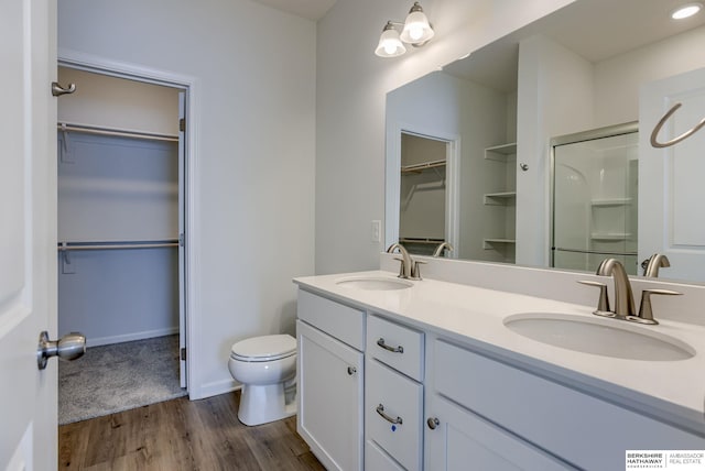 bathroom featuring wood-type flooring, vanity, toilet, and an enclosed shower