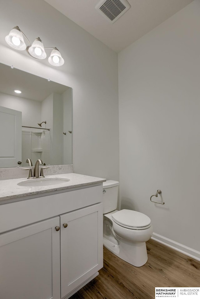 bathroom with a shower, vanity, hardwood / wood-style flooring, and toilet