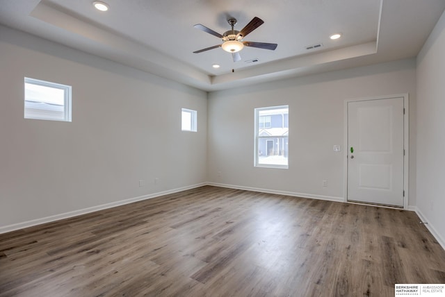 unfurnished room featuring hardwood / wood-style floors, ceiling fan, and a tray ceiling