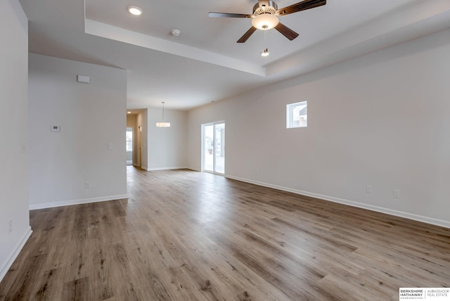 unfurnished room featuring ceiling fan, a raised ceiling, and light wood-type flooring