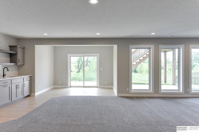 unfurnished living room with light hardwood / wood-style floors and sink