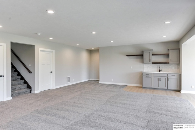 unfurnished living room with sink and light carpet