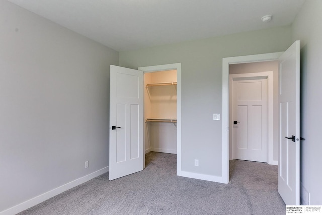 unfurnished bedroom featuring light carpet, a closet, and a spacious closet