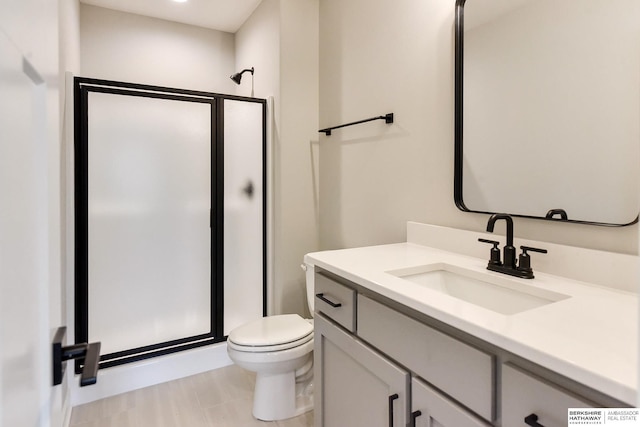 bathroom with toilet, vanity, and a shower with door