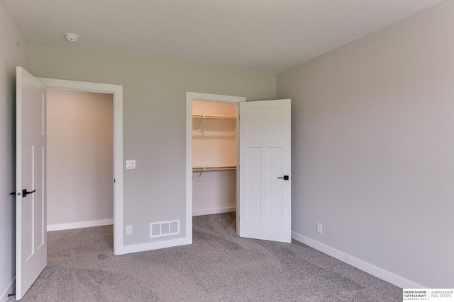 unfurnished bedroom with carpet flooring, a closet, and a spacious closet