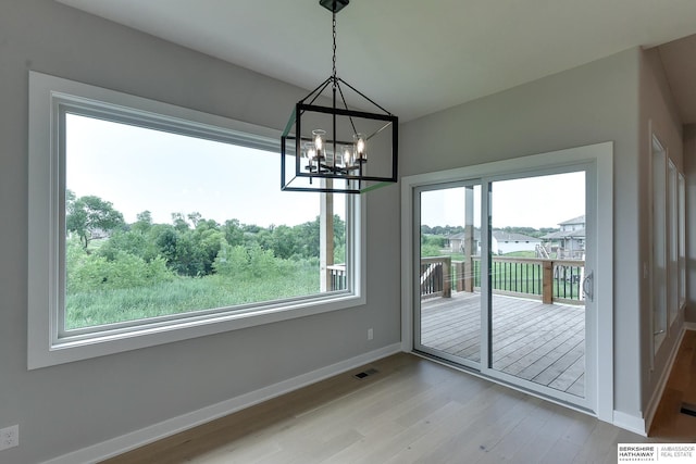 unfurnished dining area with light wood-type flooring and a notable chandelier