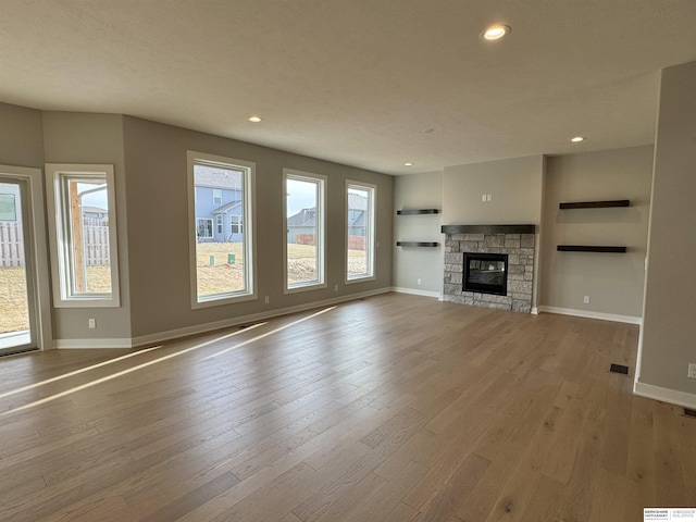 unfurnished living room with a wealth of natural light, a fireplace, and light hardwood / wood-style flooring