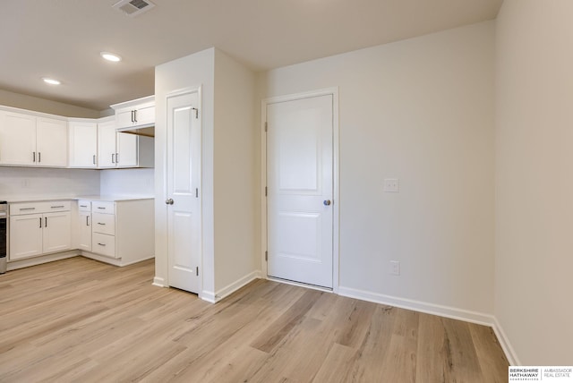 kitchen with light wood-style floors, visible vents, backsplash, and baseboards