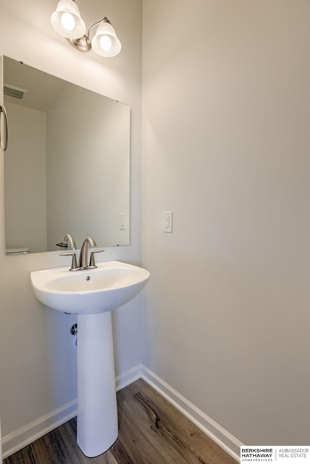 bathroom with visible vents, a sink, baseboards, and wood finished floors