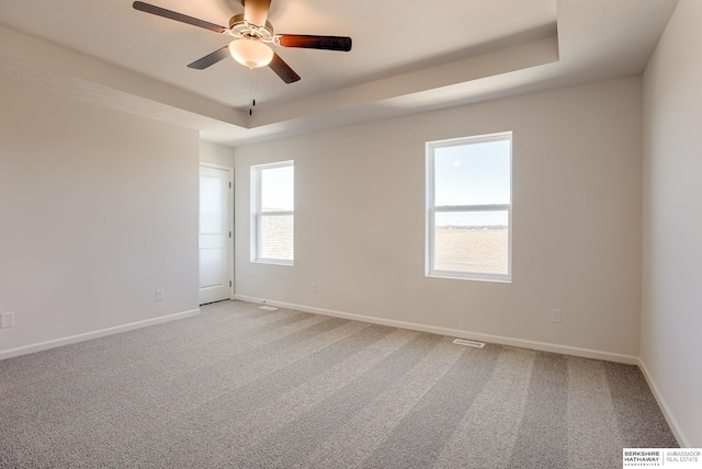 unfurnished room with light carpet, a raised ceiling, and baseboards