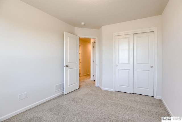 unfurnished bedroom with visible vents, carpet floors, baseboards, and a closet