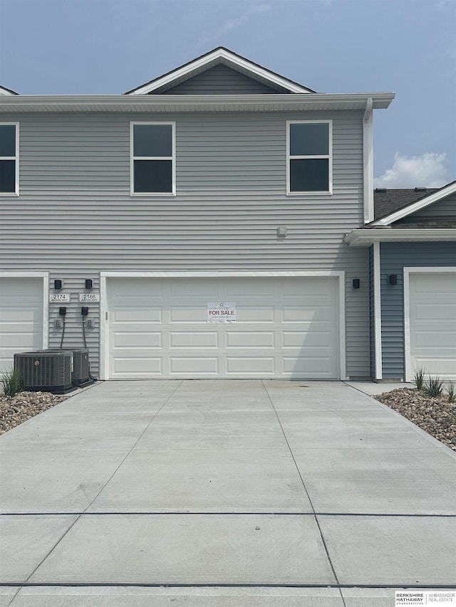 view of front of house with concrete driveway, cooling unit, and a garage