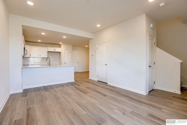 unfurnished living room with a sink, recessed lighting, and light wood finished floors