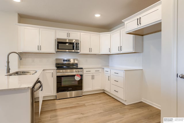 kitchen featuring white cabinetry, light wood-type flooring, appliances with stainless steel finishes, and a sink