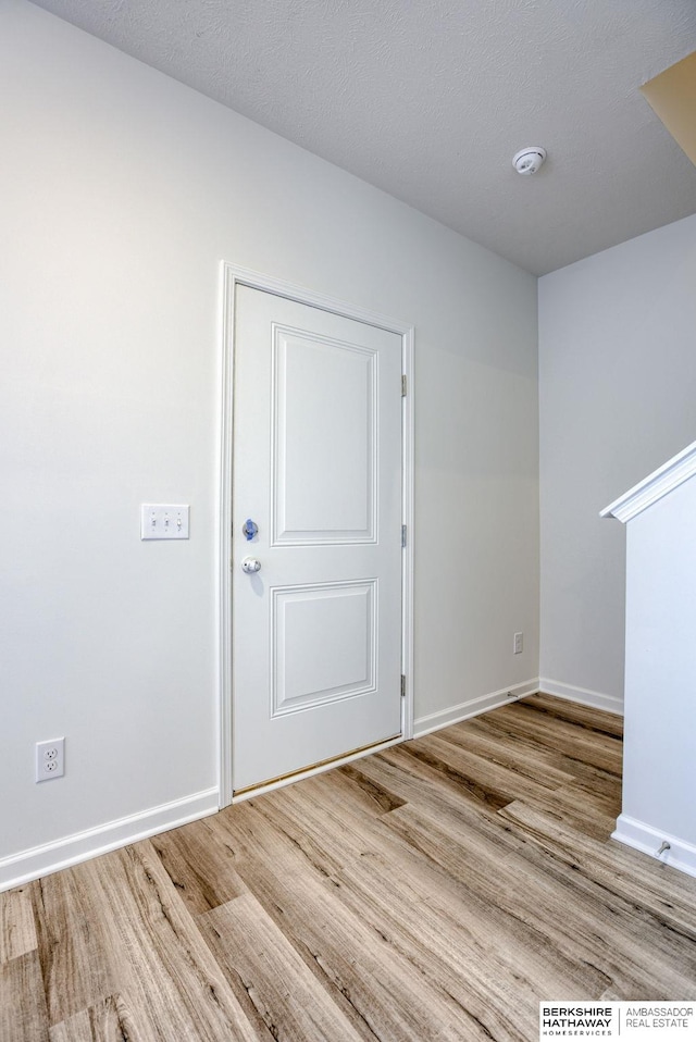 empty room with wood finished floors, baseboards, and a textured ceiling