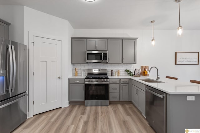 kitchen featuring appliances with stainless steel finishes, gray cabinets, hanging light fixtures, and sink