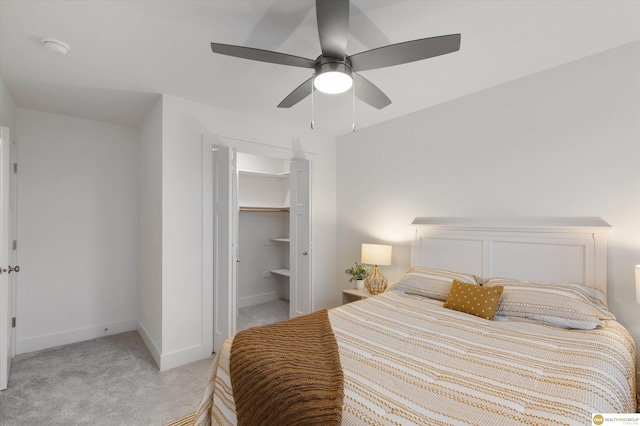 carpeted bedroom featuring a walk in closet, a closet, and ceiling fan