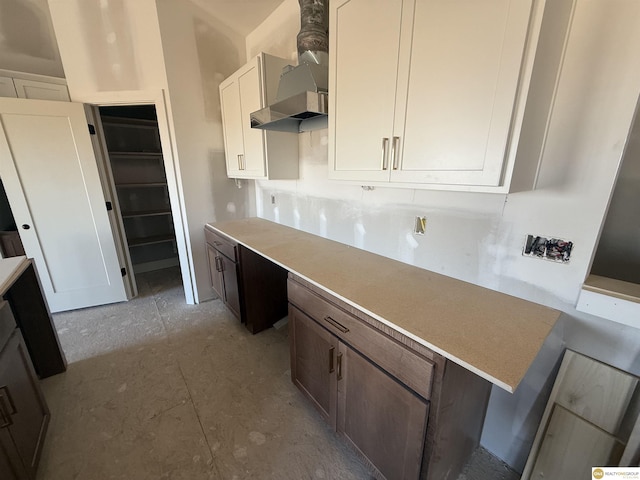 kitchen featuring white cabinetry and wall chimney range hood