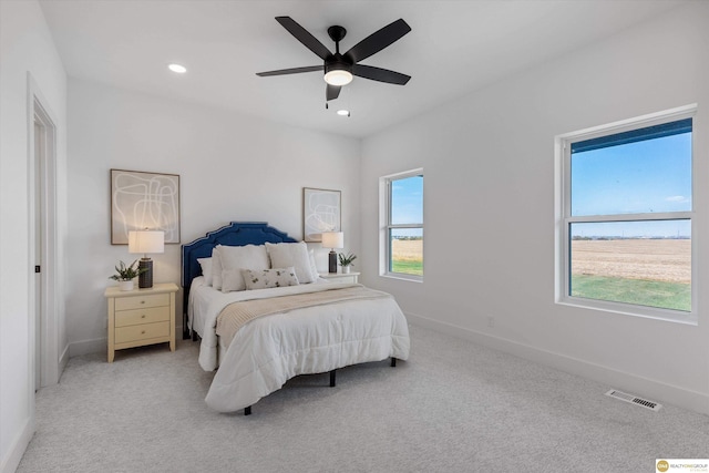 bedroom with multiple windows, light colored carpet, and ceiling fan