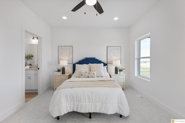 bedroom with light colored carpet, ensuite bath, and ceiling fan