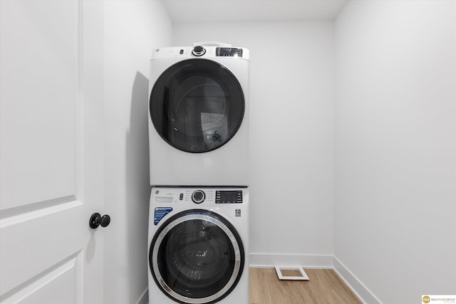 laundry area featuring wood-type flooring and stacked washer and dryer