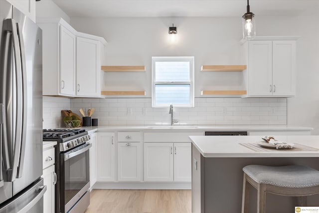 kitchen featuring sink, hanging light fixtures, stainless steel appliances, backsplash, and white cabinets