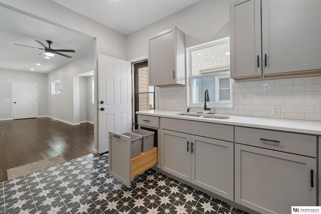 kitchen with decorative backsplash, gray cabinets, ceiling fan, and sink