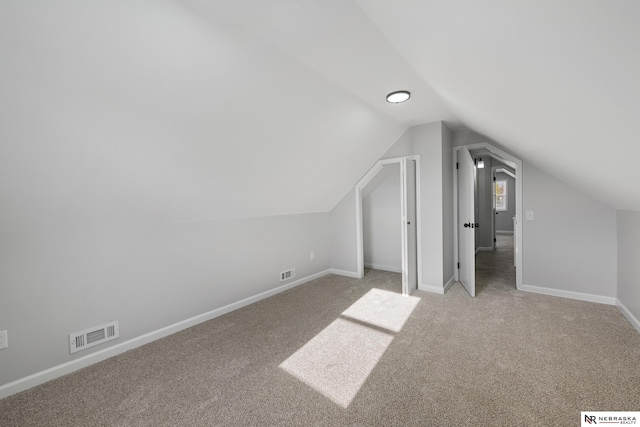 additional living space featuring lofted ceiling and light carpet