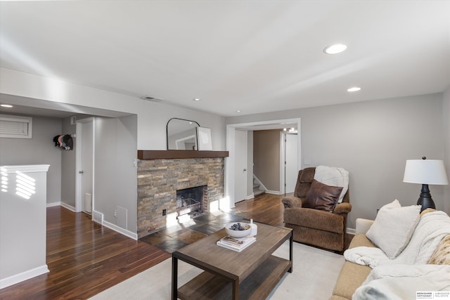 living room featuring dark hardwood / wood-style floors and a stone fireplace