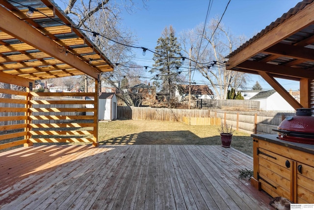 wooden terrace featuring grilling area and a storage unit