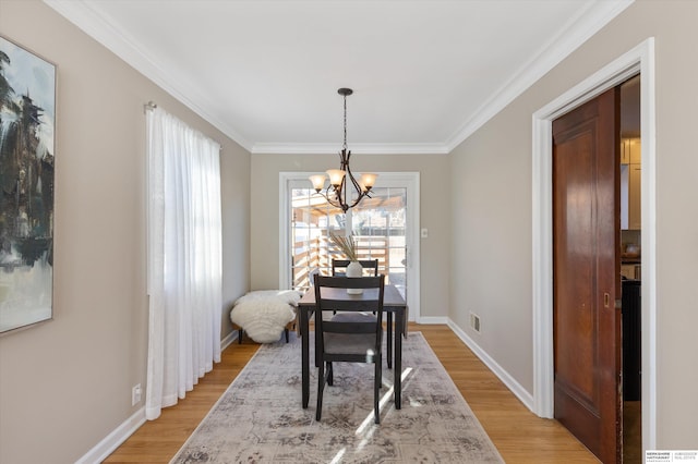 dining room featuring an inviting chandelier, ornamental molding, and light hardwood / wood-style flooring