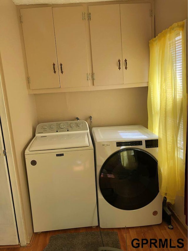 washroom featuring washer and dryer, light hardwood / wood-style floors, and cabinets