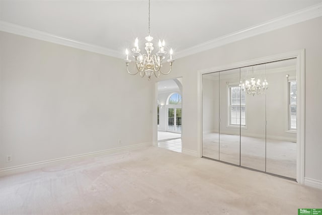 spare room featuring light carpet, a chandelier, and ornamental molding