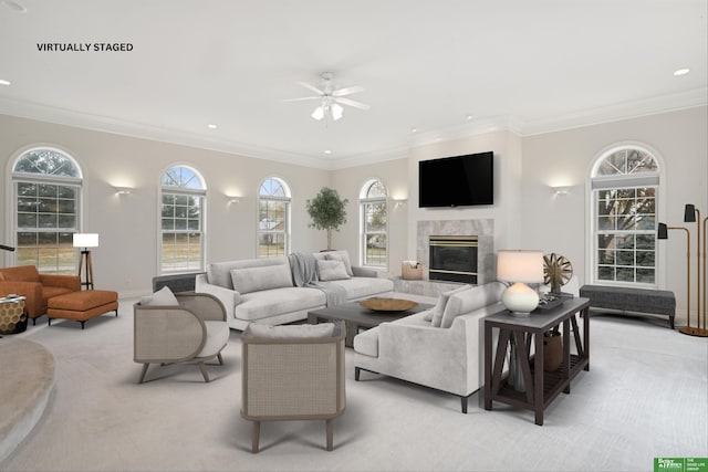 carpeted living room with a premium fireplace, crown molding, and ceiling fan