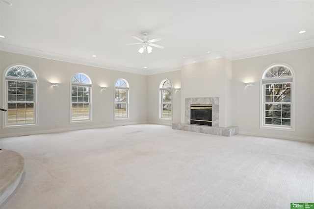 unfurnished living room with ceiling fan, ornamental molding, light carpet, and a high end fireplace